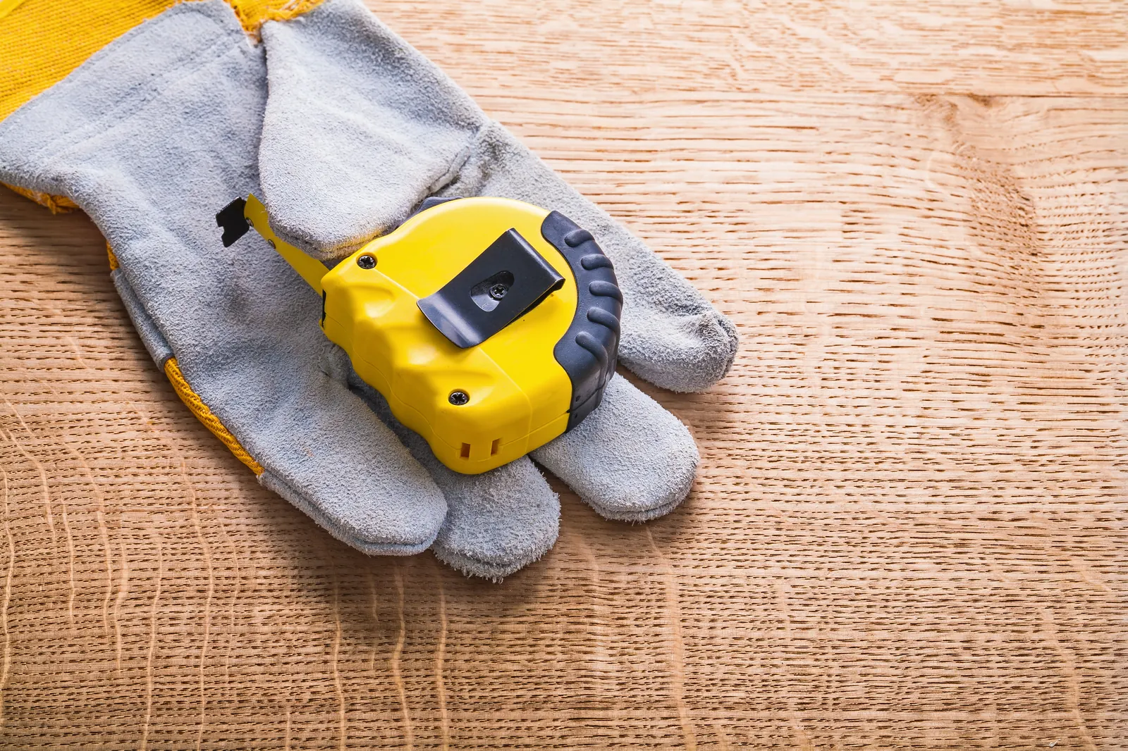 Arbeitshandschuhe und Massband auf Holz